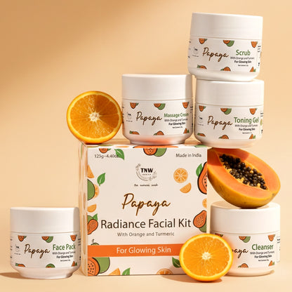 Papaya facial kit with various products and papaya and orange slices on a beige background